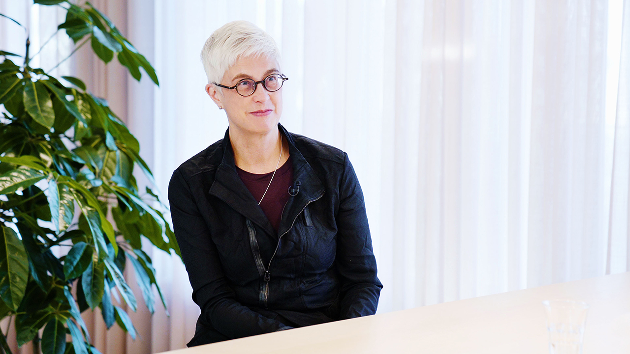 Person sittandes vid ett bord med en stor växt bakom