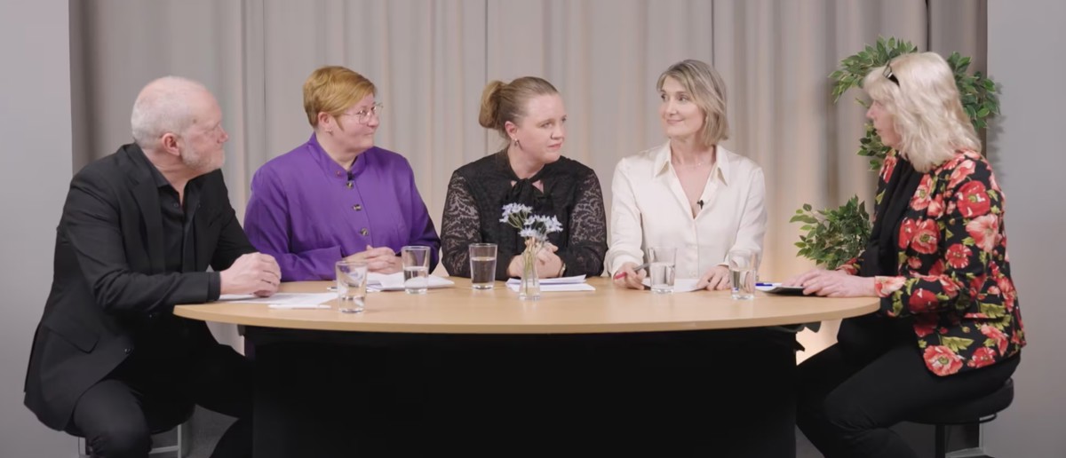 Fem personer sitter runt ett bord i en studio.