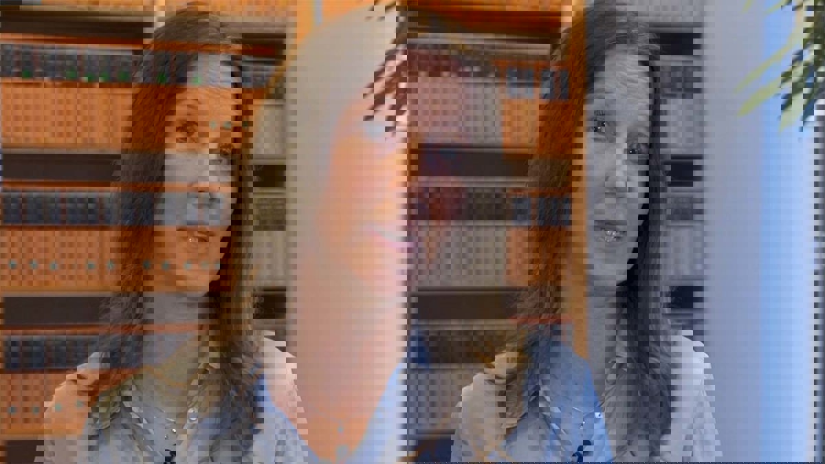 Person framför bokhylla fylld med orangesvarta böcker.