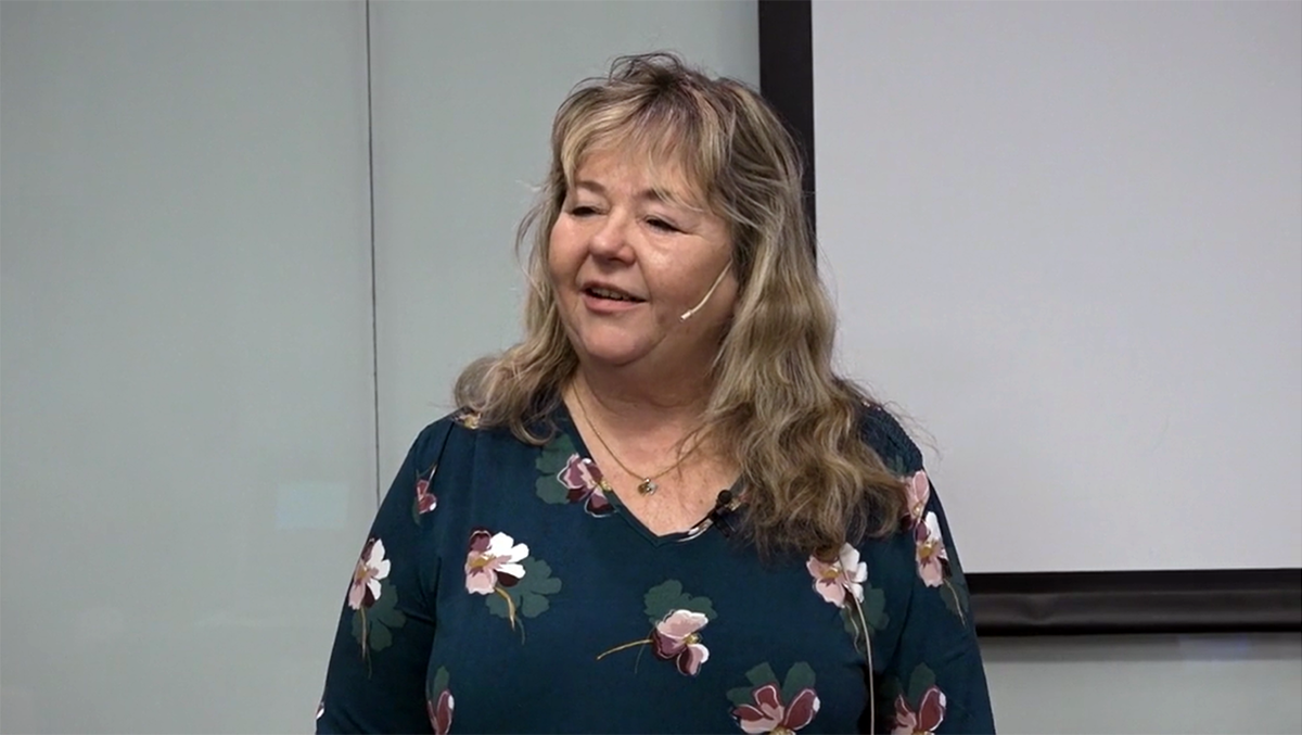 Person med mikrofonheadset framför vit tavla.