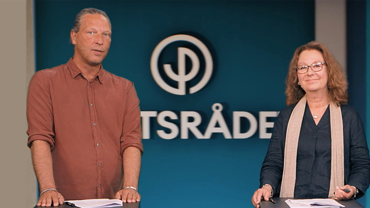 Två personer står i en filmstudio och tittar in i kamera. Bakom syns Partsrådets logotyp.