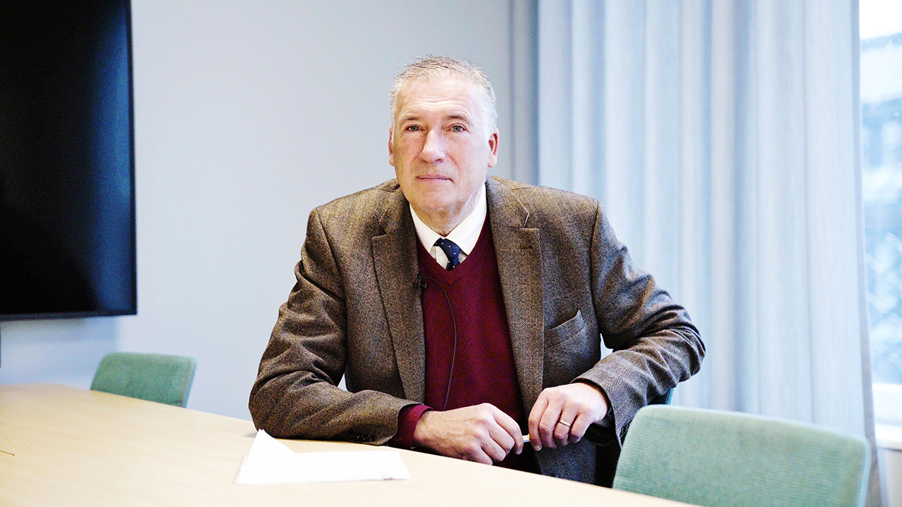 Person sittandes vid ett mötesbord med ett stort fönster i bakgrunden.