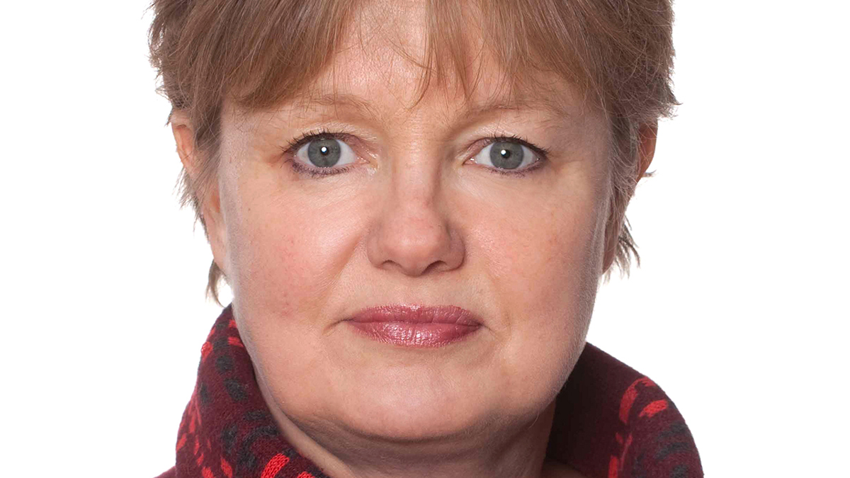 Person med kort hår iklädd en röd tröja med stor krage.