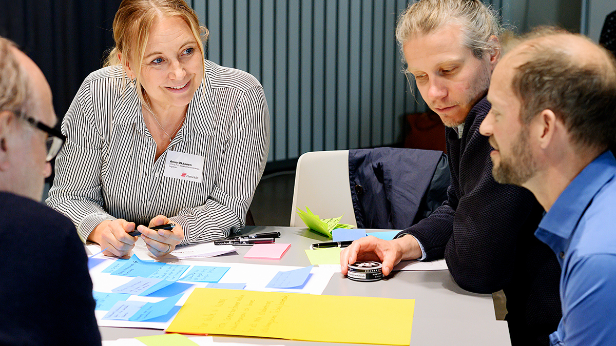 Bild på fyra personer som för ett samtal runt ett bord.