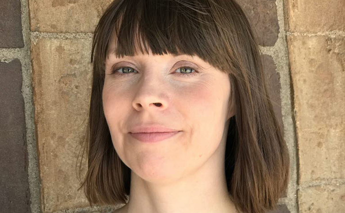 Person framför tegelvägg.