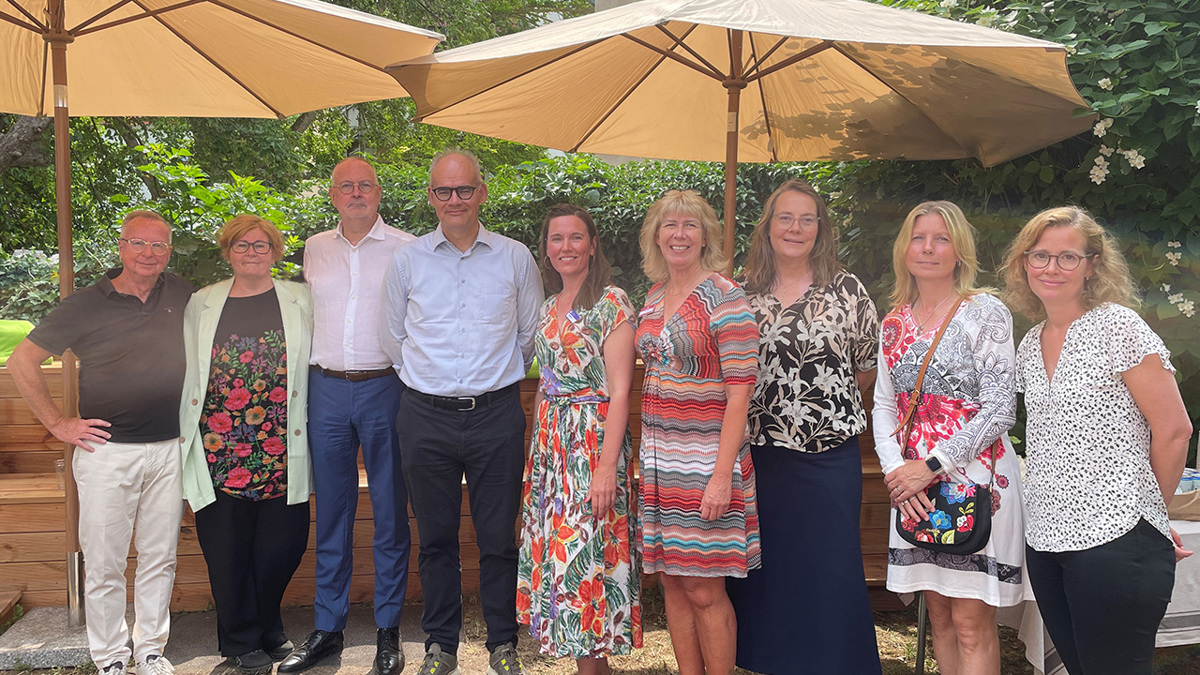 Nio personer står i en trädgård under parasoll efter seminarium