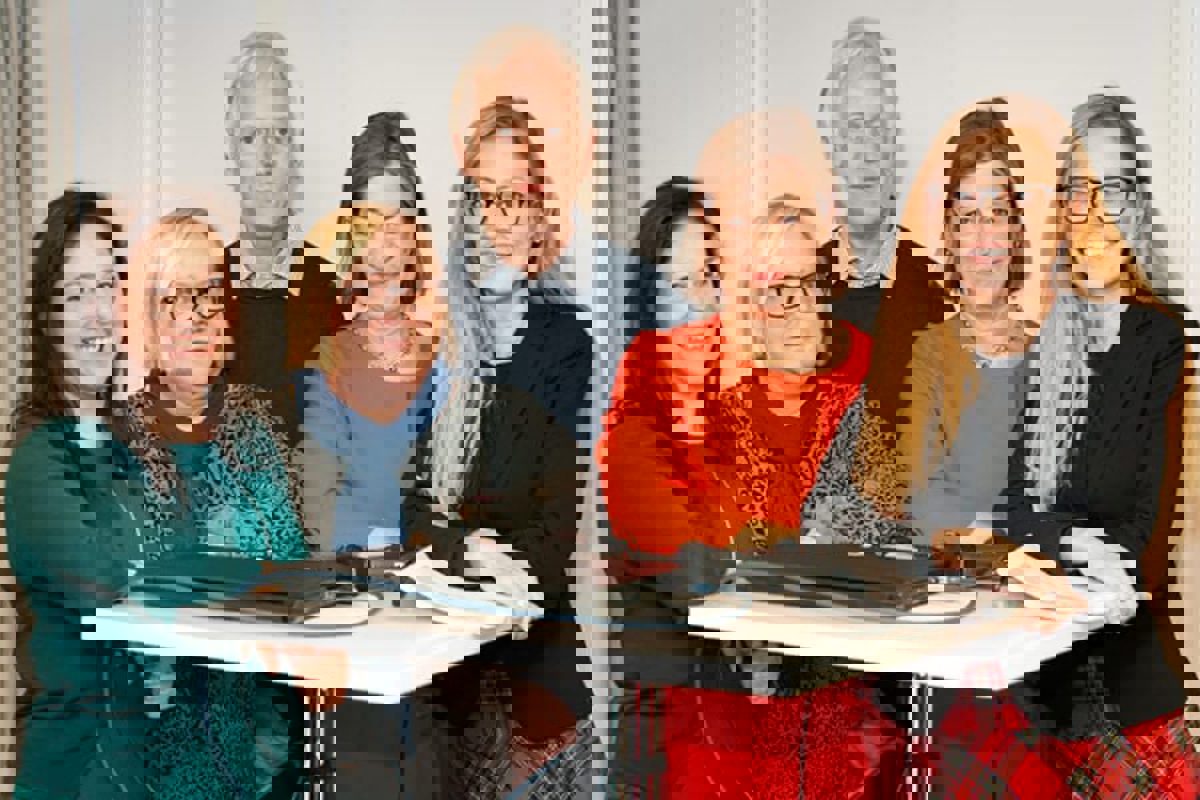 Fem personer runt ett ståbord med blicken riktad mot kameran.