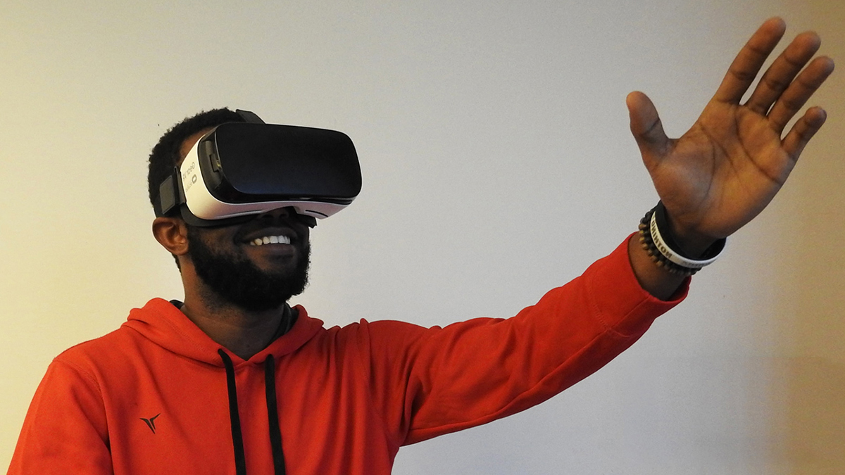 Person iförd VR-glasögon och med ena handen höjd framför sig.