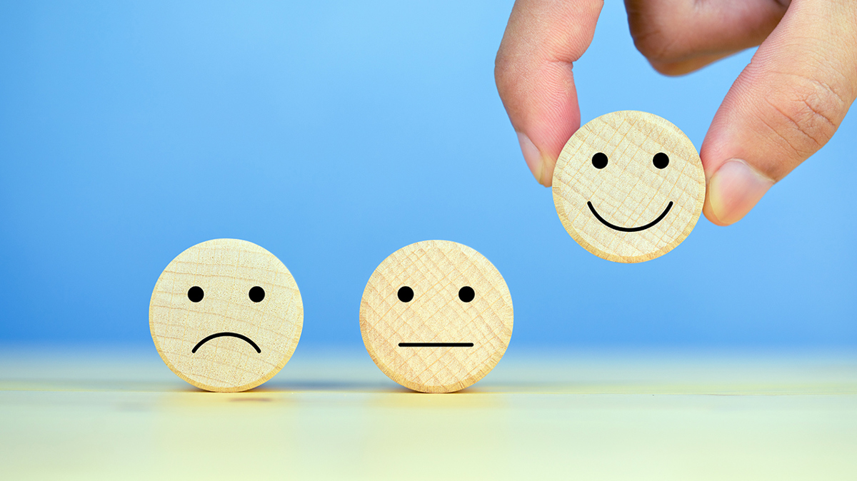 Tre smileygubbar i trä, varav den första är missmöjd, den andra är neutral och den sista är glad.