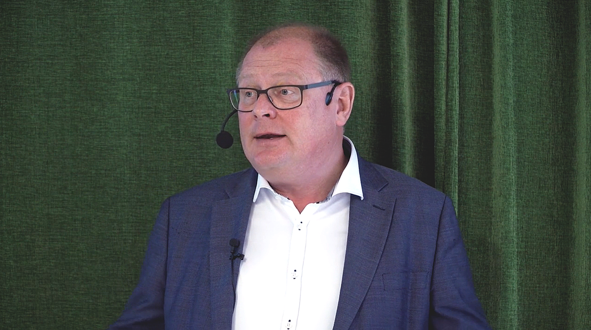 Person med headseatmikrofon framför grönt draperi.