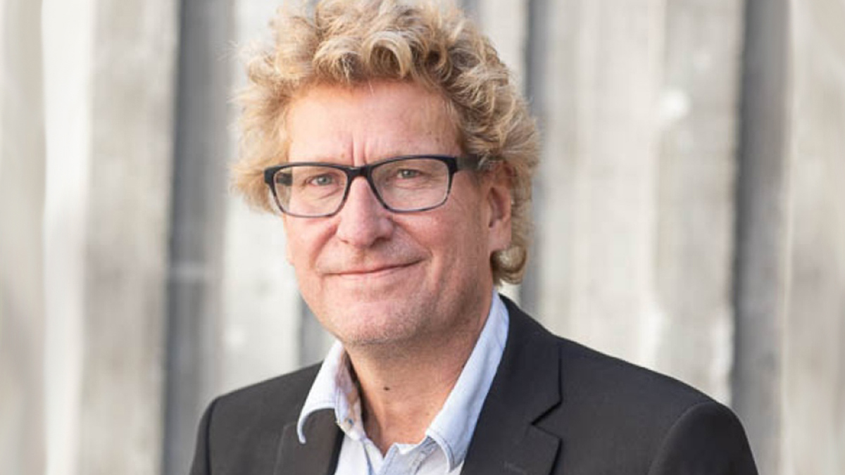 Person iförd mörkgrå kostym och skjorta, samt glasögon.