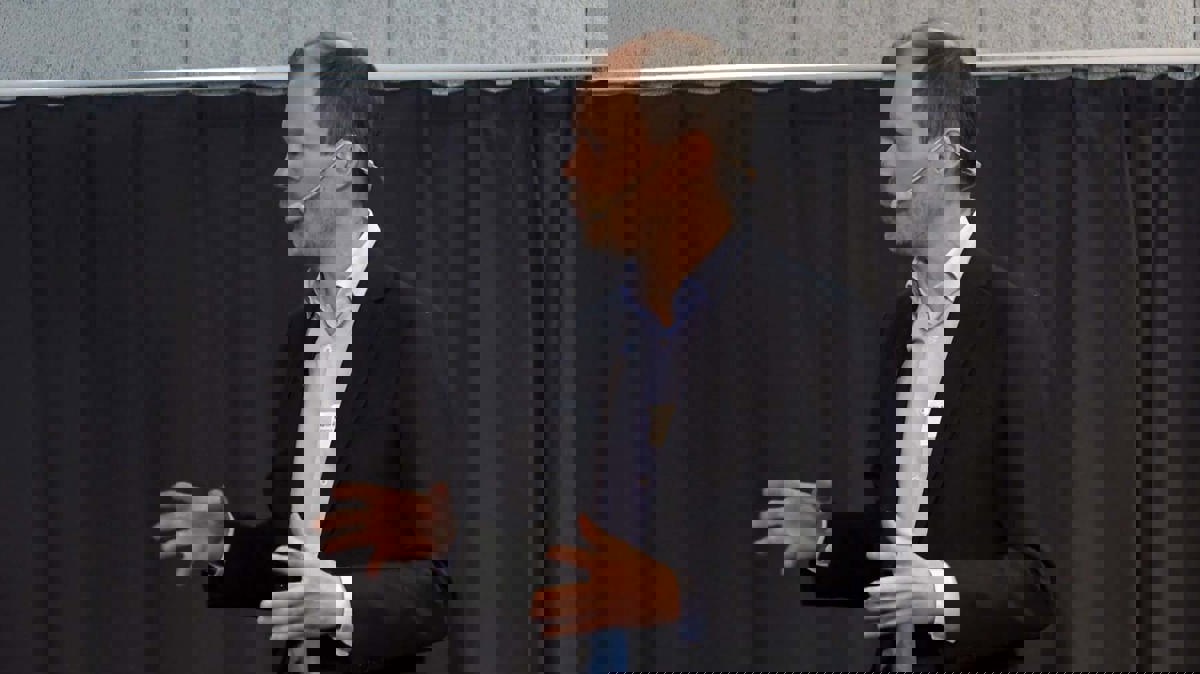 Person i föreläsningssituation iförd mikrofonheadset, svart kavaj och ljus skjorta.